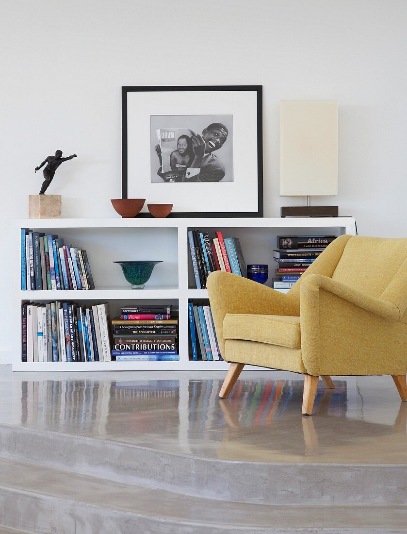 50s armchair in front of half-height shelving unit on concrete platform with steps