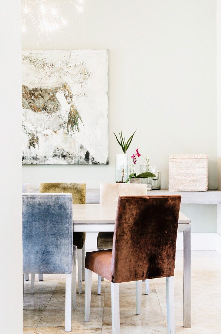 Gepolsterte Stühle mit Samtbezug an modernem Tisch in minimalistischem Esszimmer