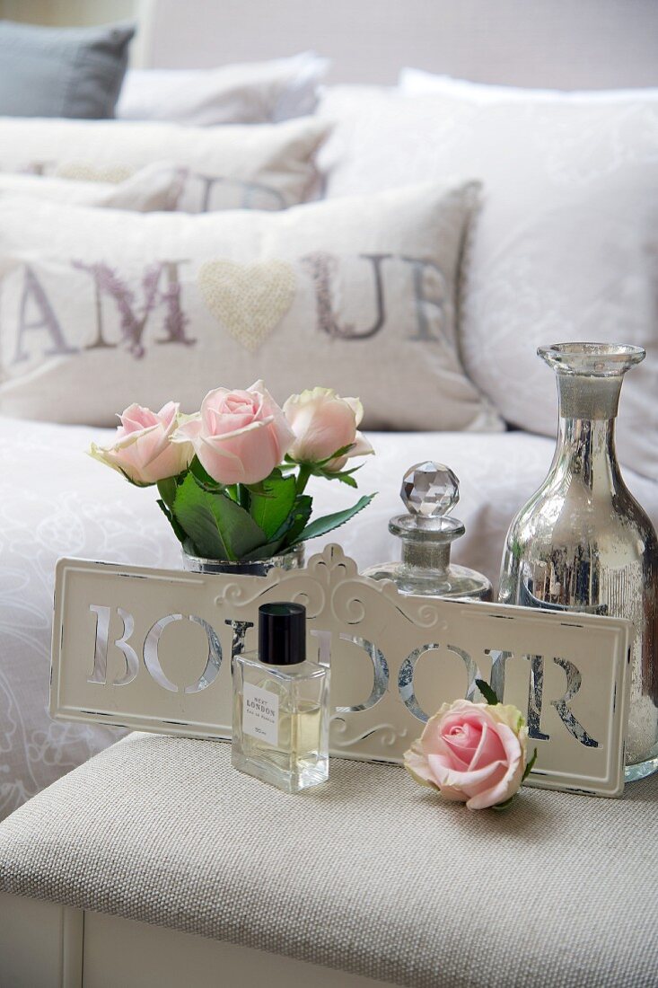 Nachttisch mit Rosen, Parfüm und Silbervase