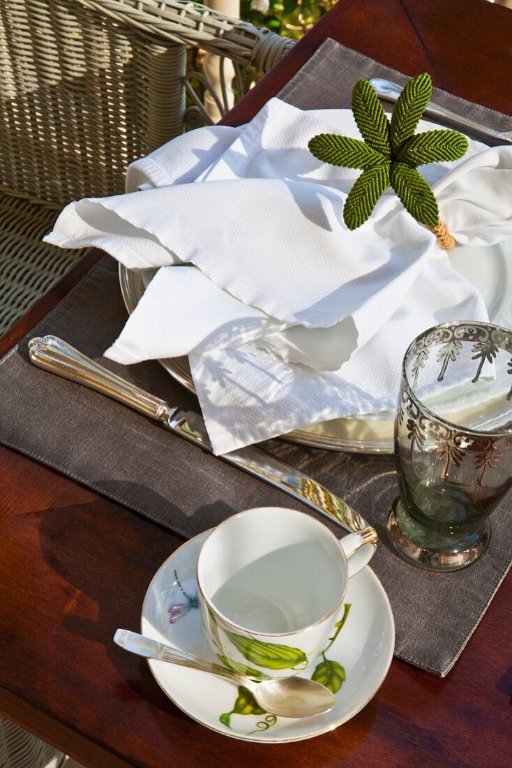 Frühstücksgedeck mit Blumendeko und weisser Stoffserviette auf Holztisch