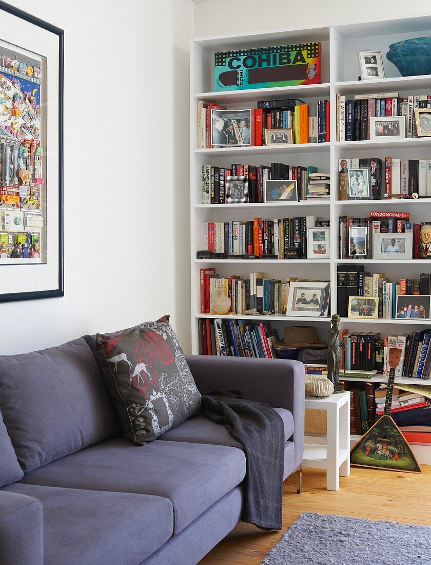 Modern, purple sofa in front of bookcase in corner of living room