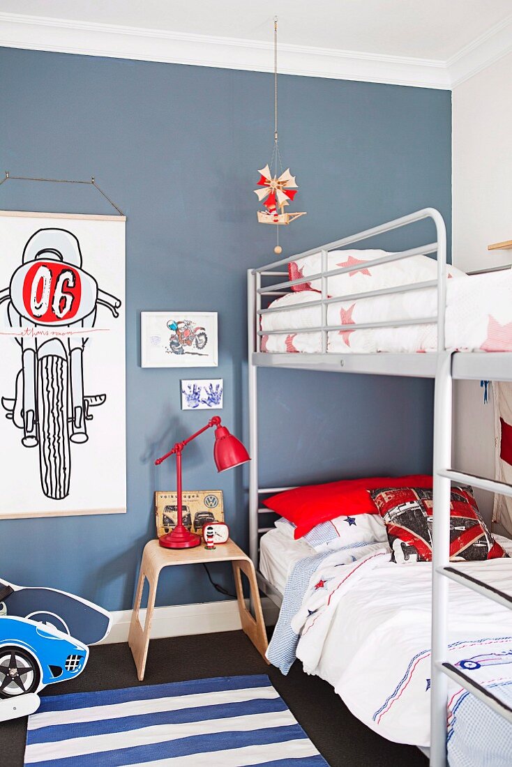 Metal-framed bunk beds in blue-painted teenagers' bedroom with drawings of motorbikes on wall