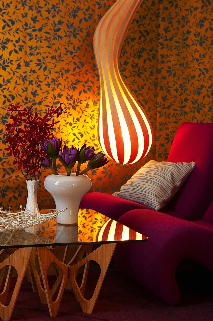 Gestreifte Designer-Lampe, Sessel und Glastisch in Wohnzimmerecke