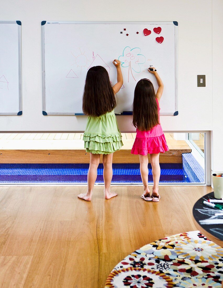 Two girls drawing on magnetic whiteboard