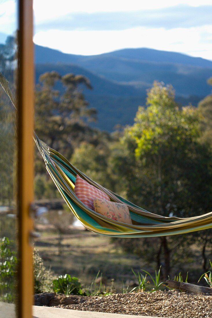 Hammock with pillows swinging above a terrace with mountains in the background