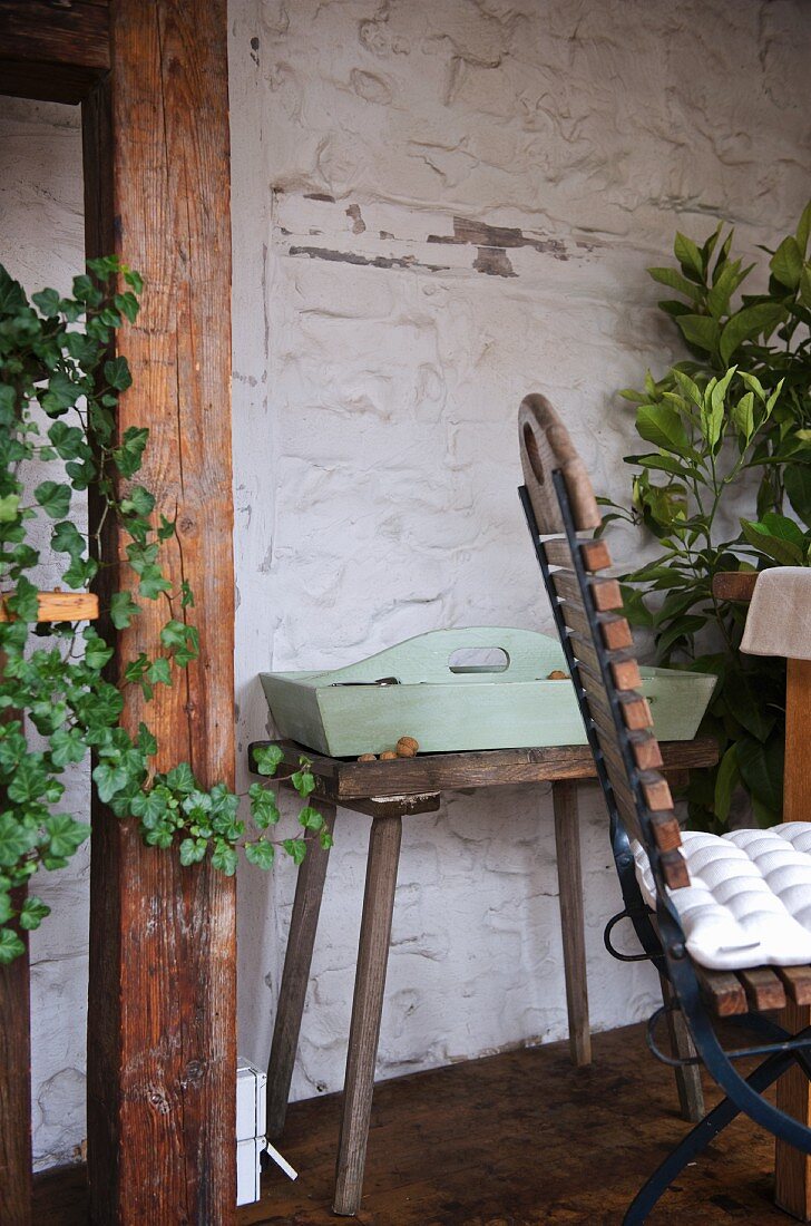 Pastel green tray on vintage stool against rustic wall in conservatory