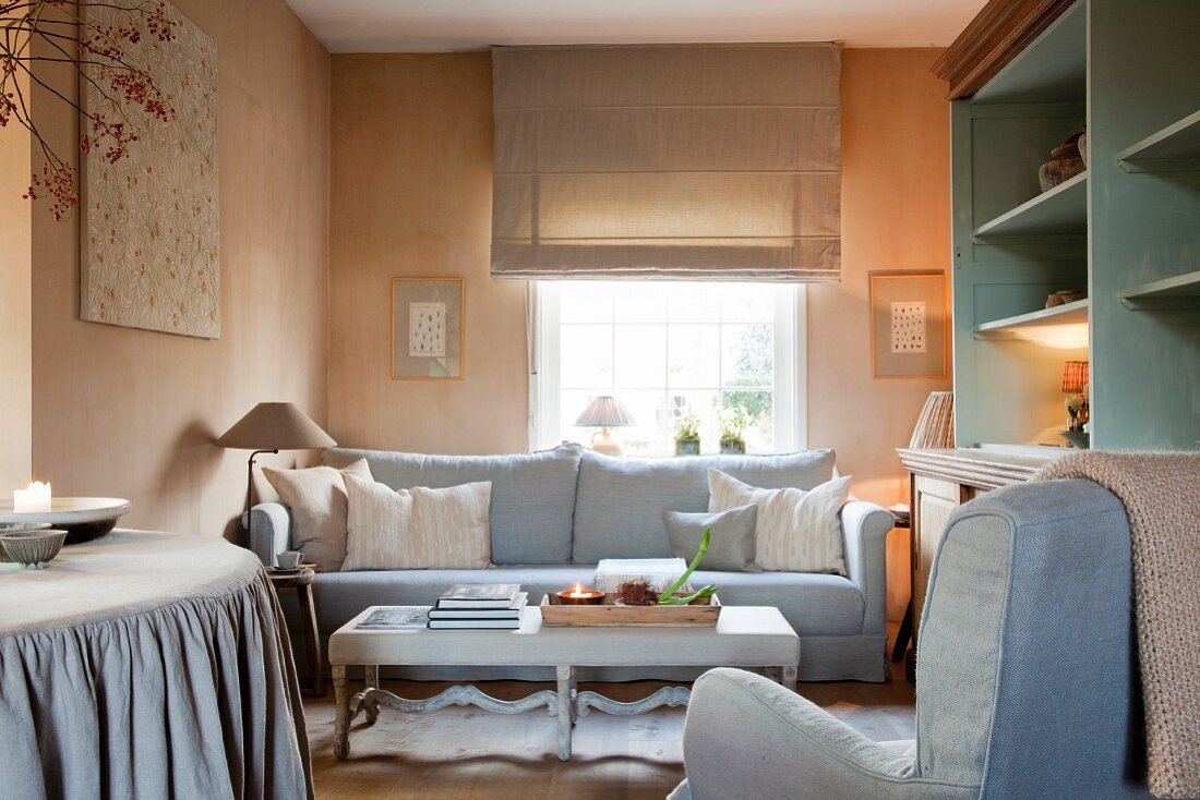 Subtle colour scheme in interior with pastel-painted walls and furnishings with grey upholstery