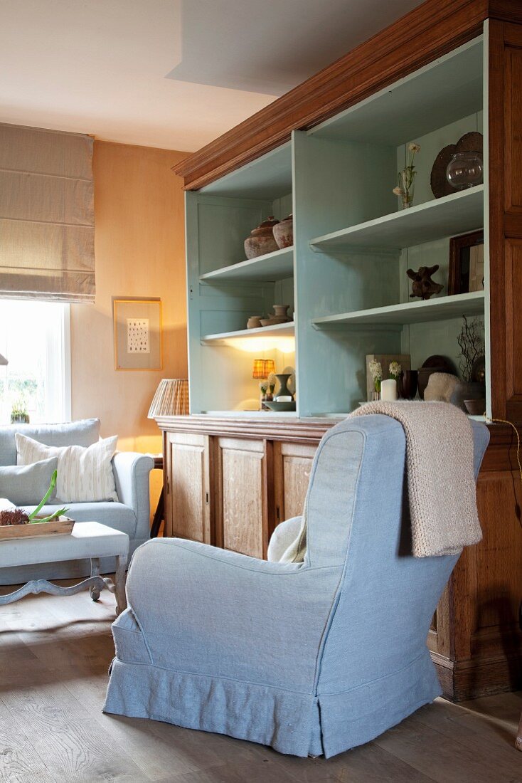 Armchair next to country-style dresser with open-fronted shelves