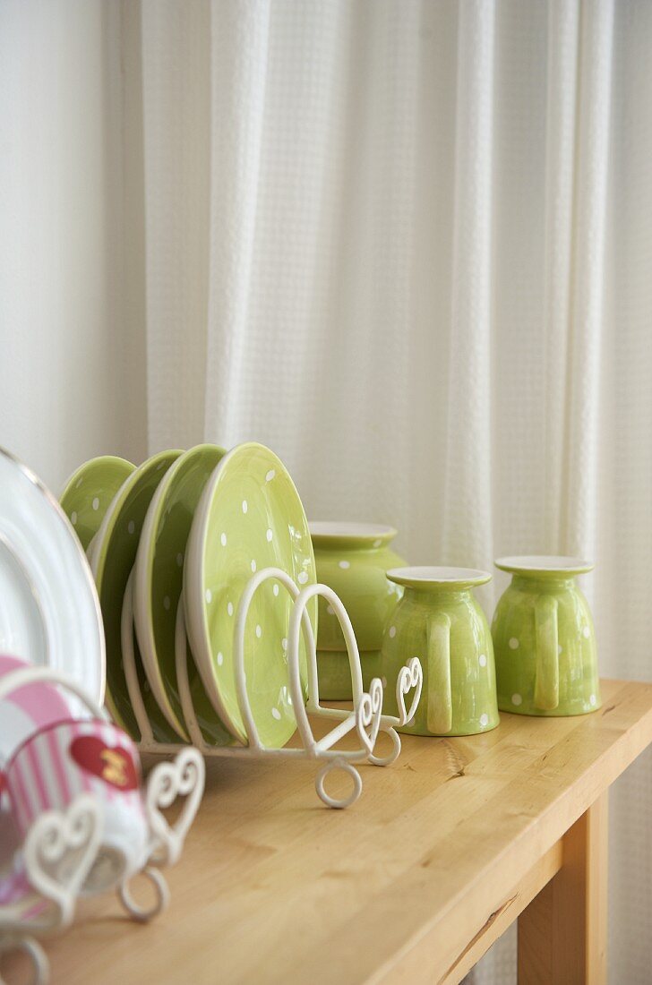 Fröhliches Geschirr in Pastellgrün mit weissen Pünktchen auf Holztisch