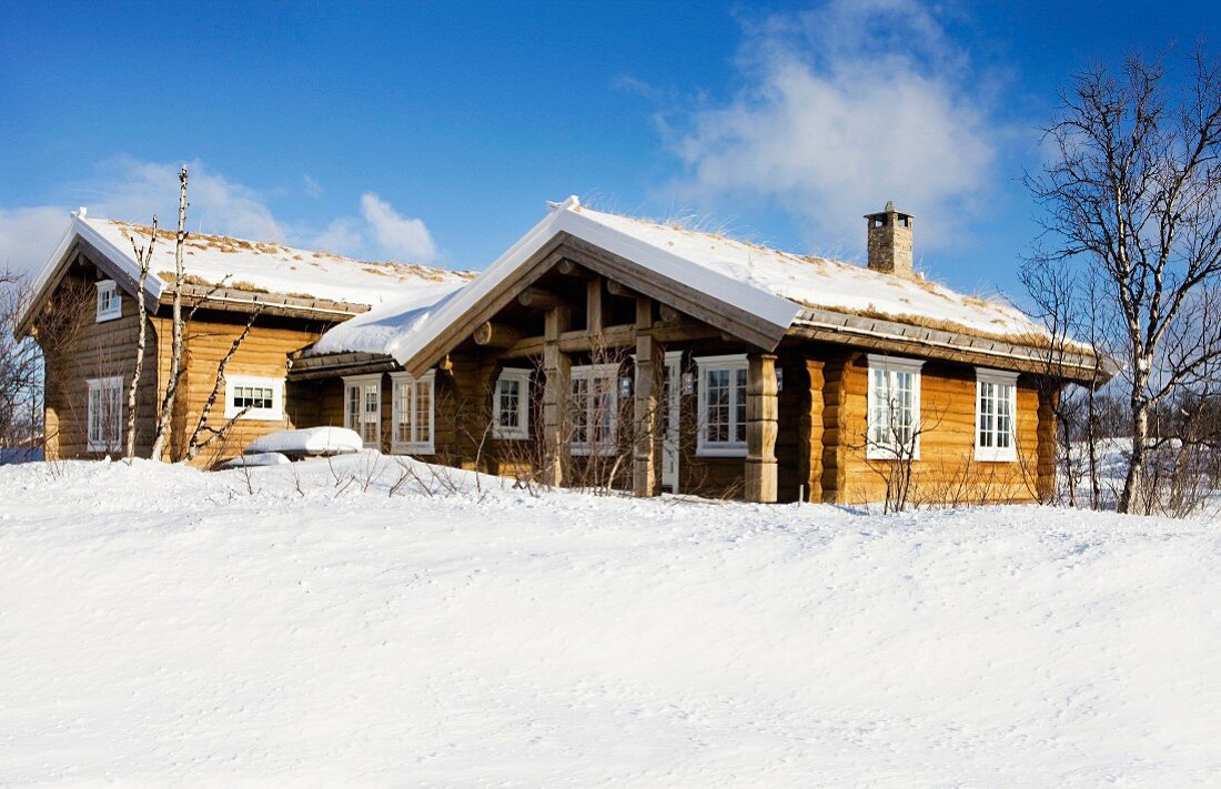 Holzhäuser in verschneiter Winterlandschaft und blauer Himmel