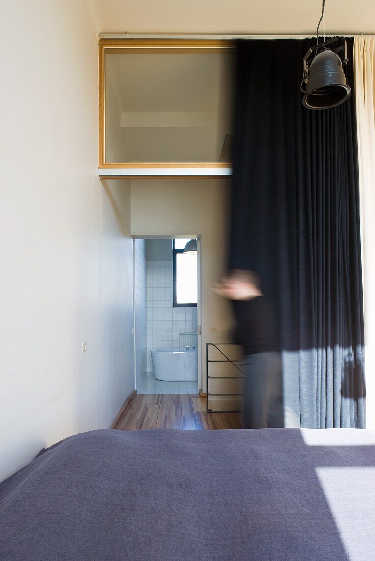 Blick über das Doppelbett in das Bad Ensuite hinter dunklem Vorhang