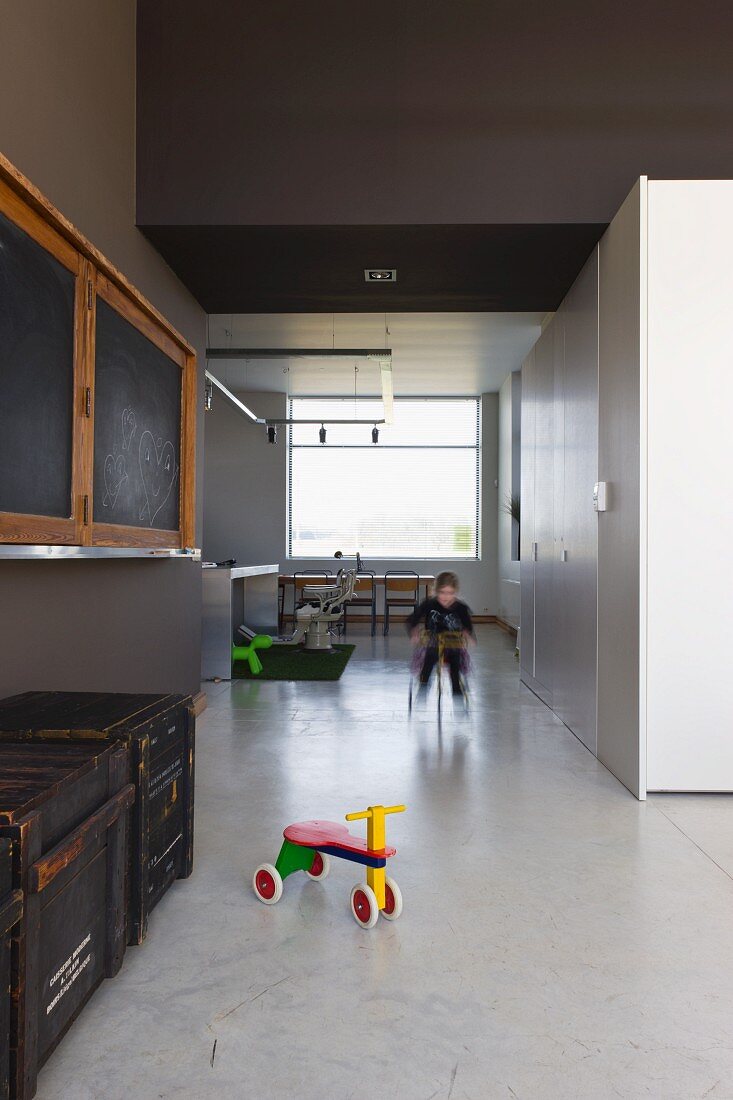 Purist living-dining room in converted school building: play area with polished concrete floor