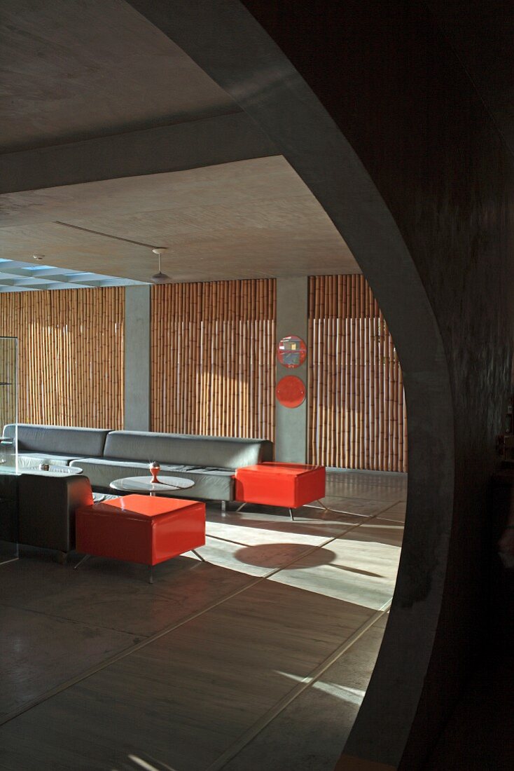 Purist hotel lounge with straw mats and bright red accents combined with grey exposed concrete and rectangular sofas
