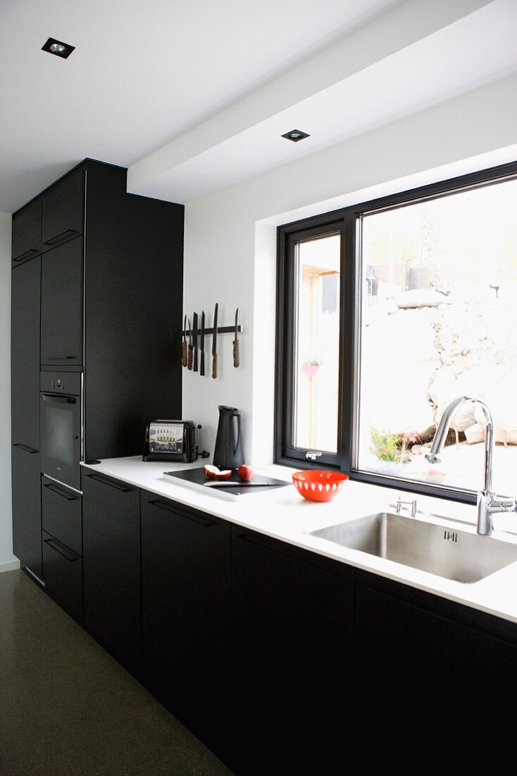 Küchenzeile mit Einbauschrank in Schwarz an Wand mit Fenster