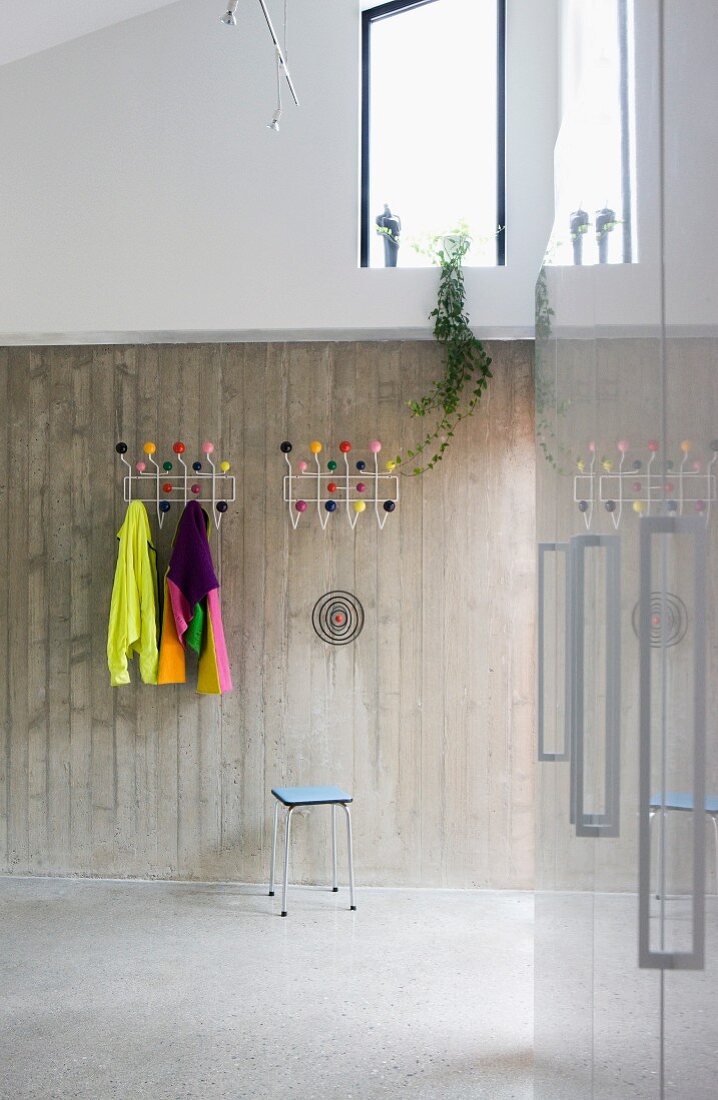 Garderobe mit bunten Kugeln an Sichtbetonwand in modernem Vorraum
