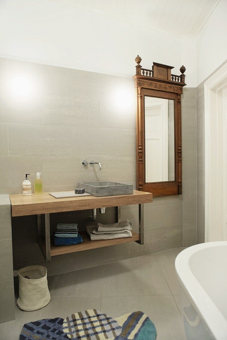 Moderner Waschtisch neben Wandspiegel mit antikem Holzrahmen im Designer-Bad