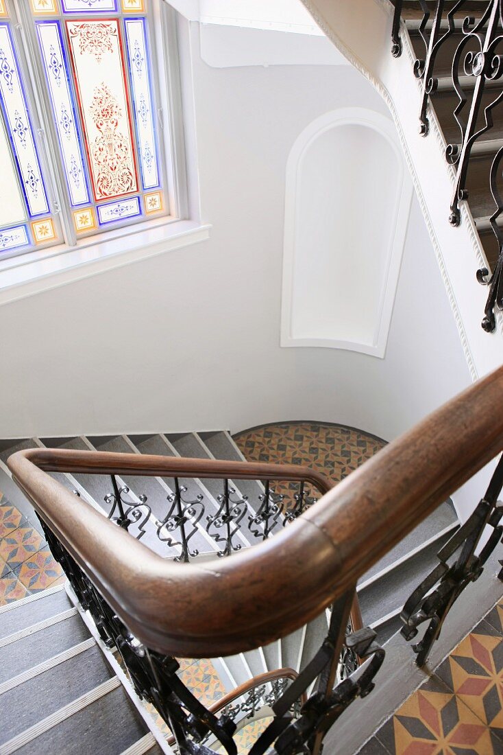 Traditional stairwell with stained glass window and patterned tiled floor