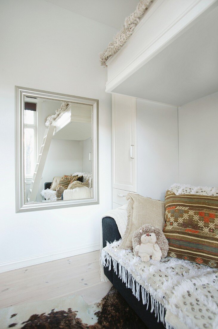 Zimmerecke mit Hochbett und Sofa neben gerahmtem Wandspiegel