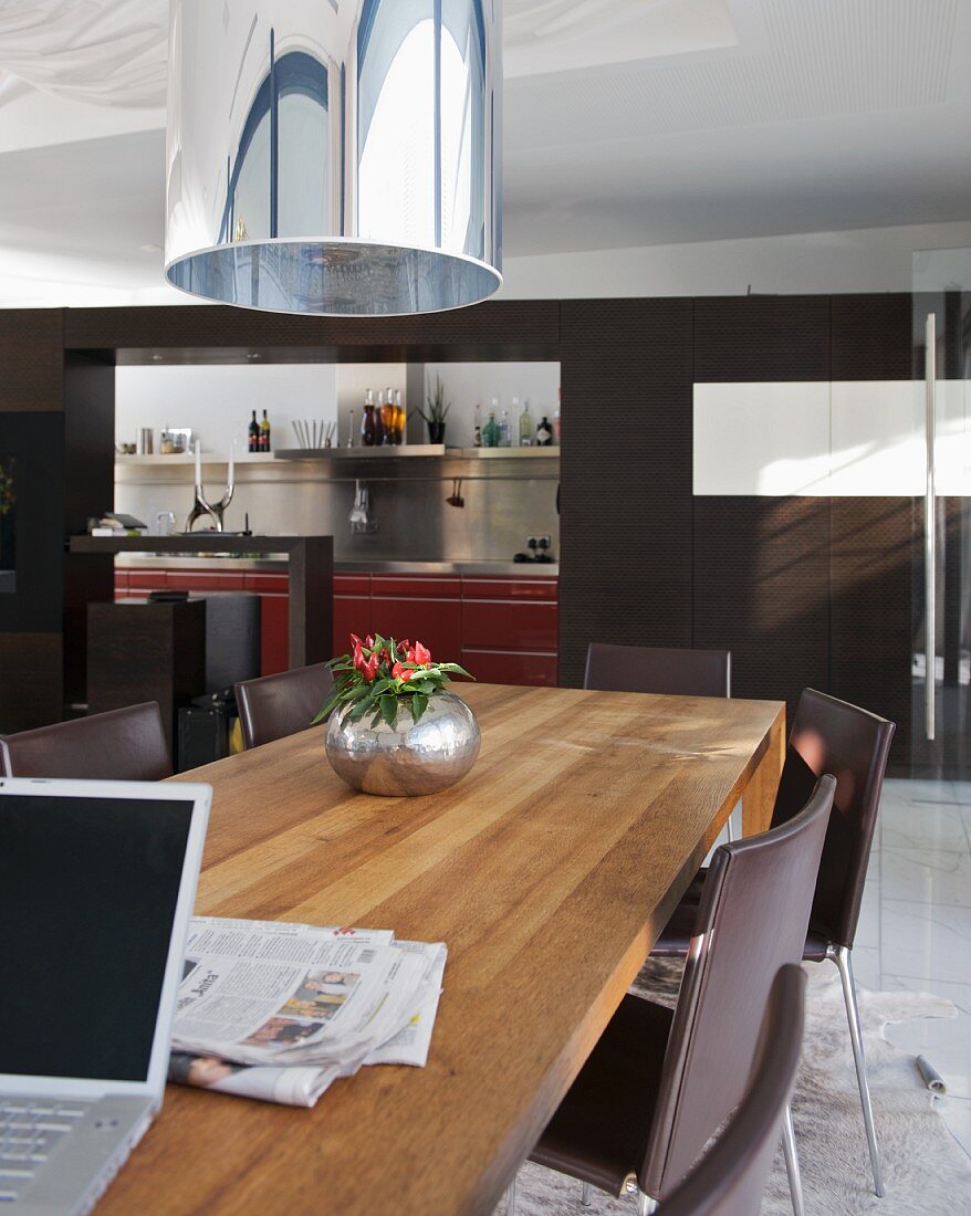 Moderner Holztisch und Stühle im Wohnzimmer mit schwarz getöntem Raumteiler und breitem Durchgang vor Küche