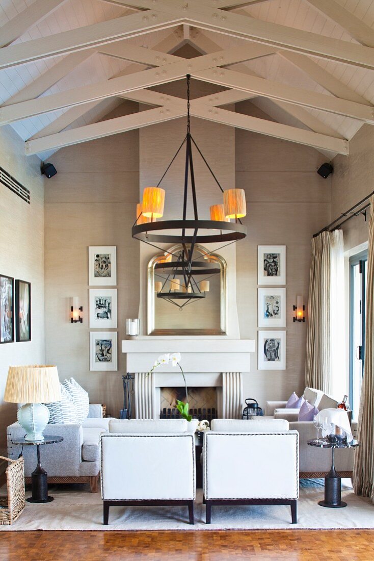 Eleganter Loungebereich mit offenem Kamin unter schmiedeeisernem Kerzenleuchter an Holzkonstruktion der Decke