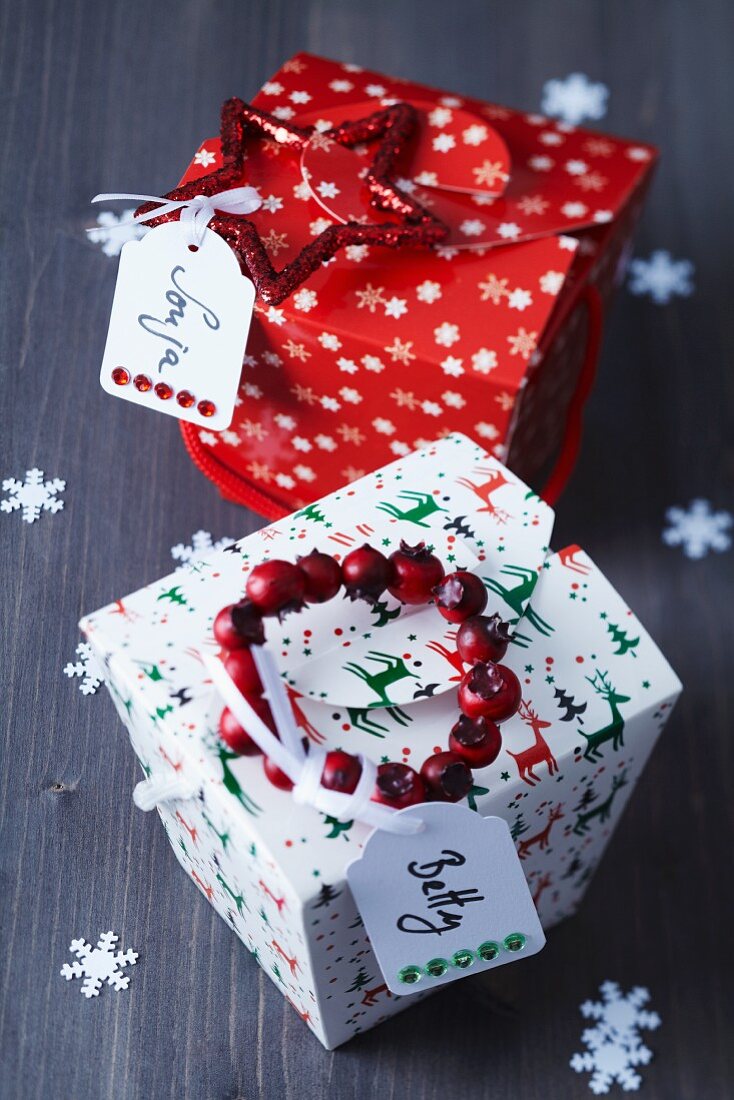Festive, folded card gift boxes with name tags, glittery star and wreath of rosehips