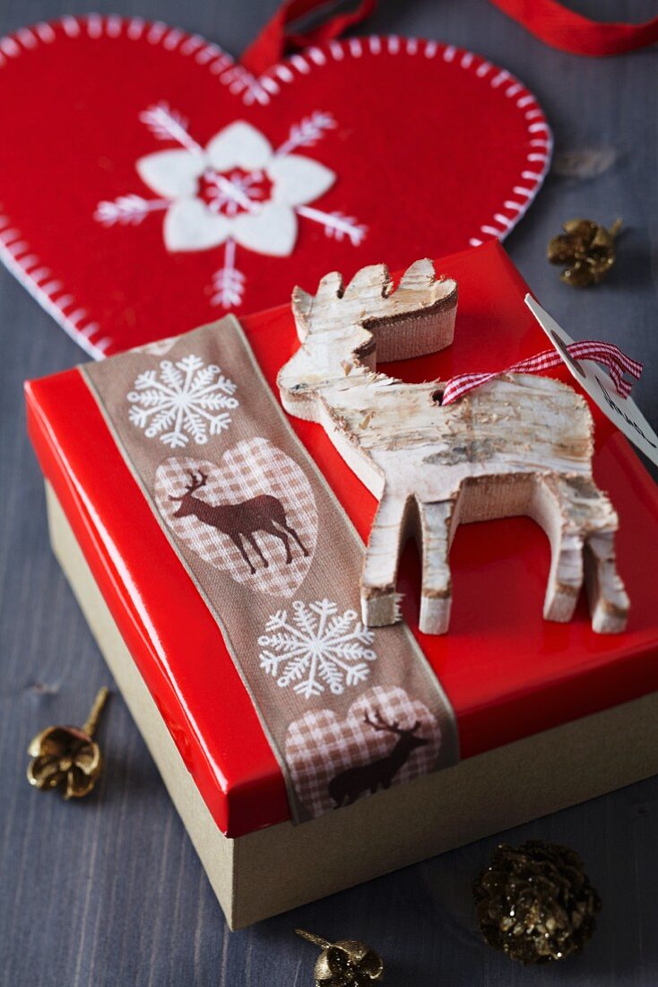 Rentieranhänger auf Weihnachtlich dekorierte Geschenkschachtel mit Rentierband
