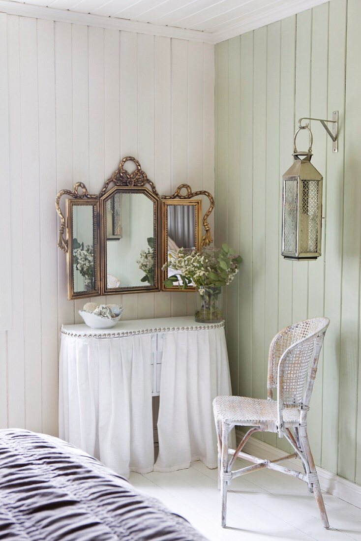 Curved console table with white curtains and wall-mounted, gilt-framed mirror in corner of wood-clad room