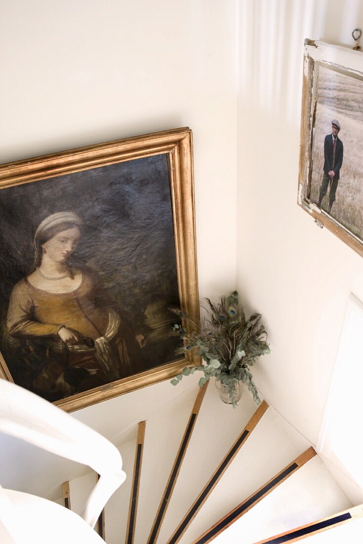 Gerahmte Bilder in Treppenabgang; kontrastierende Gestaltung mit weiss belegten Holzstufen und schwarzen Streifen
