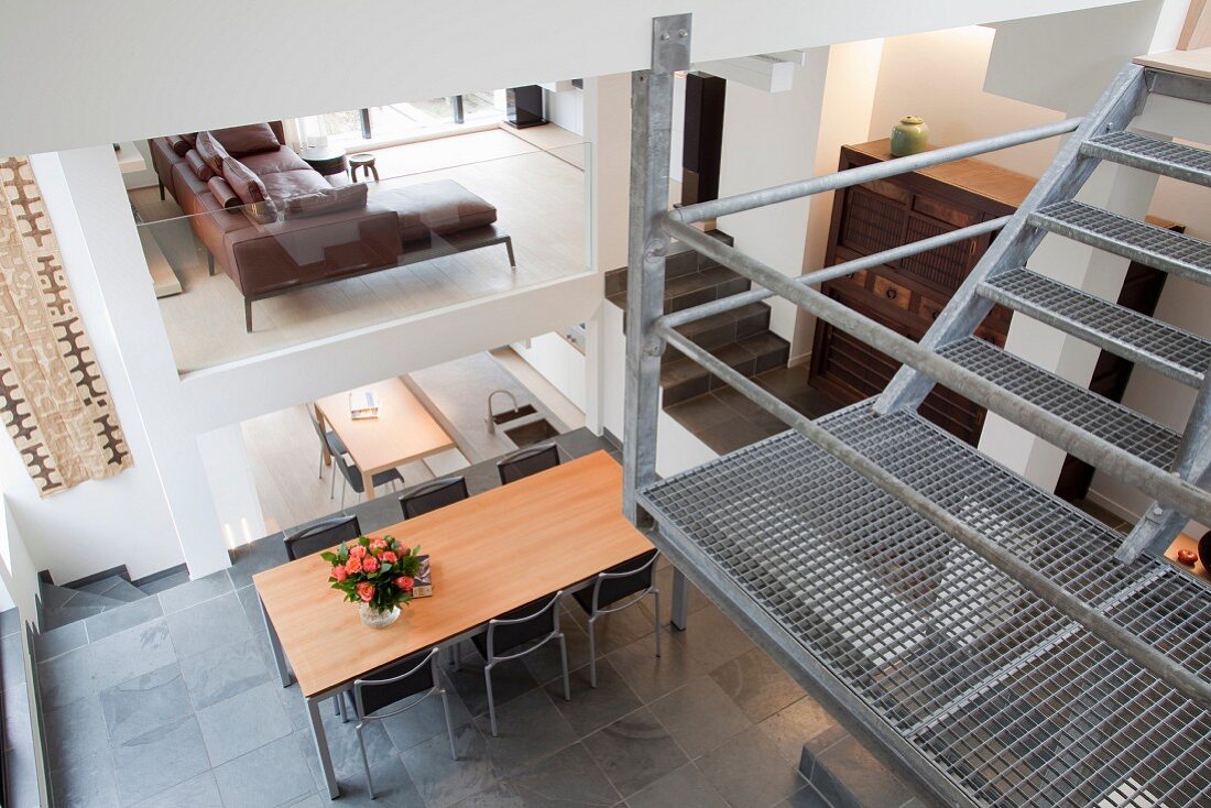 Landing of wire mesh staircase in open-plan interior with seating on various levels