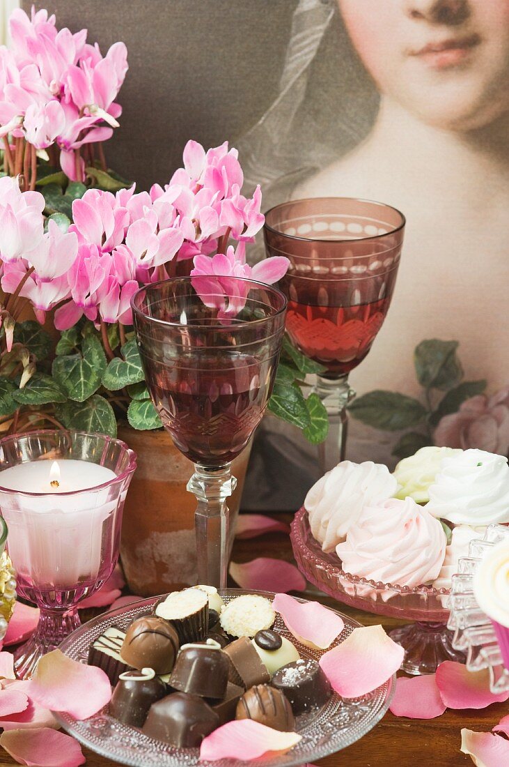 Baisergebäck, Pralinen, Weingläser, Kerzen und Cyclamen in Blumentöpfen