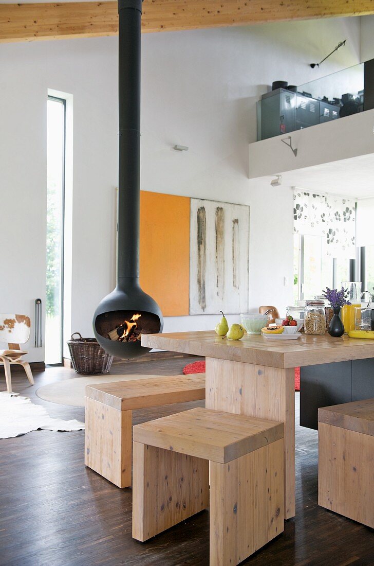 Plain, pale wooden stools and table in open-plan interior with Chimney Anthrax Bubble fireplace by Andrea Crosetta