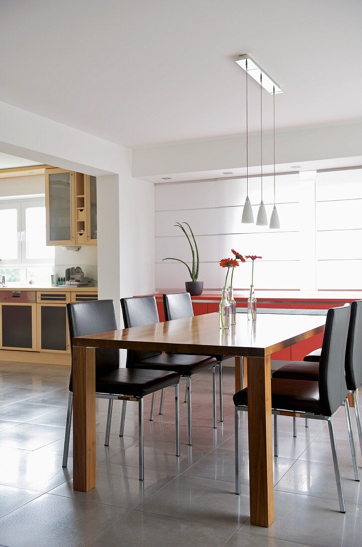 Designer-Essplatz in offenem Wohnraum mit Blick durch breiten Durchgang auf Küchenzeile