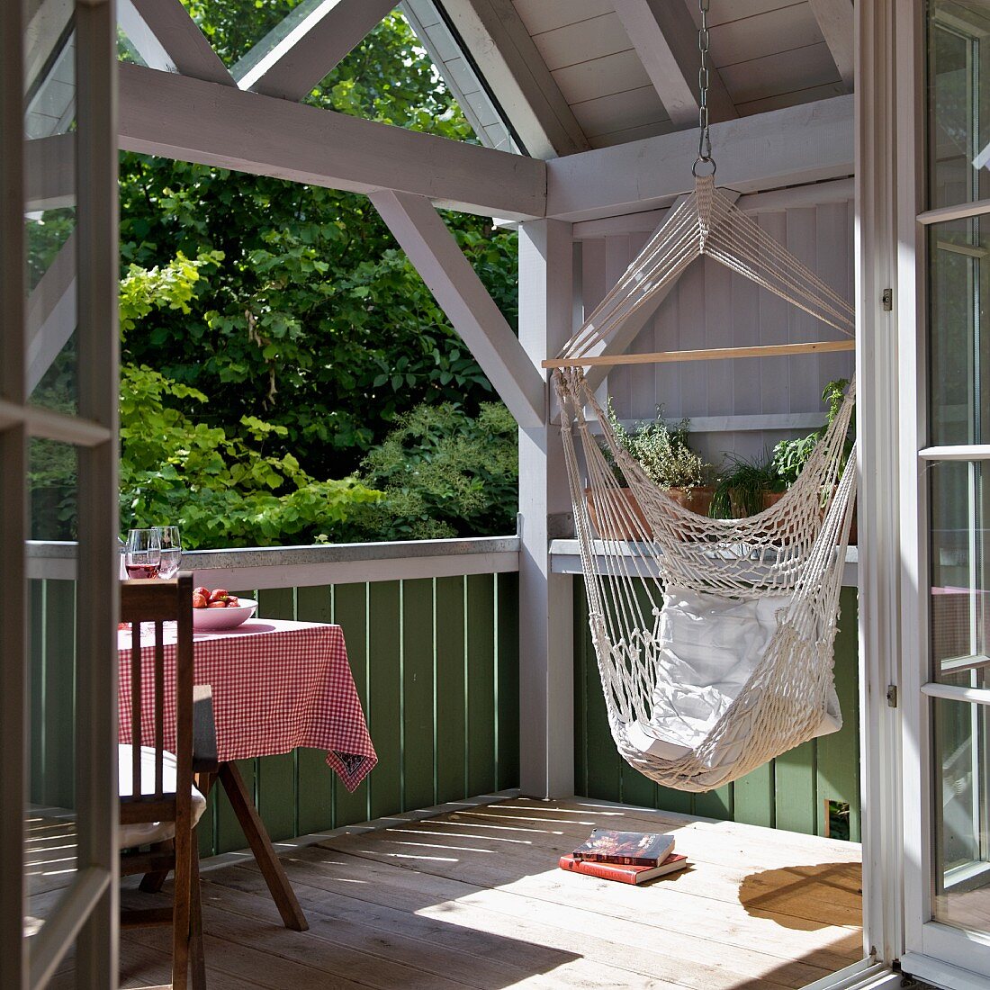 Chillen in der Hängematte - Blick durch offene Tür auf sonnenbeschienenen Balkon eines Holzhauses