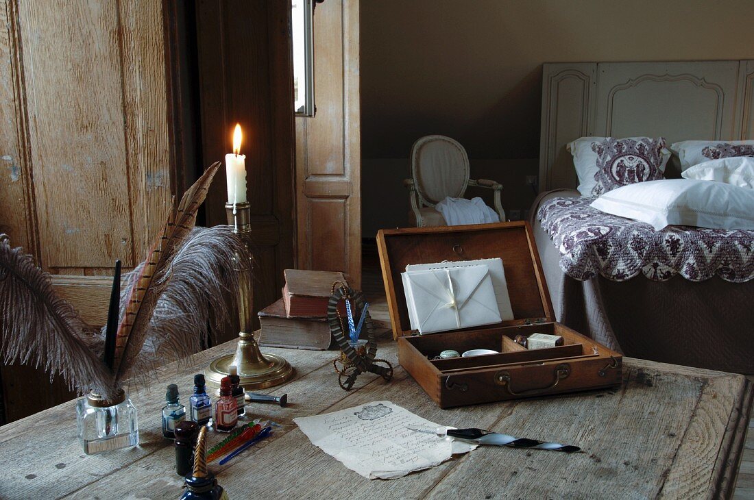 Alter Tisch in Schlafzimmer - stilvoll dekoriert mit Federkielen, silbernem Kerzenleuchter und geöffneter Briefschatulle