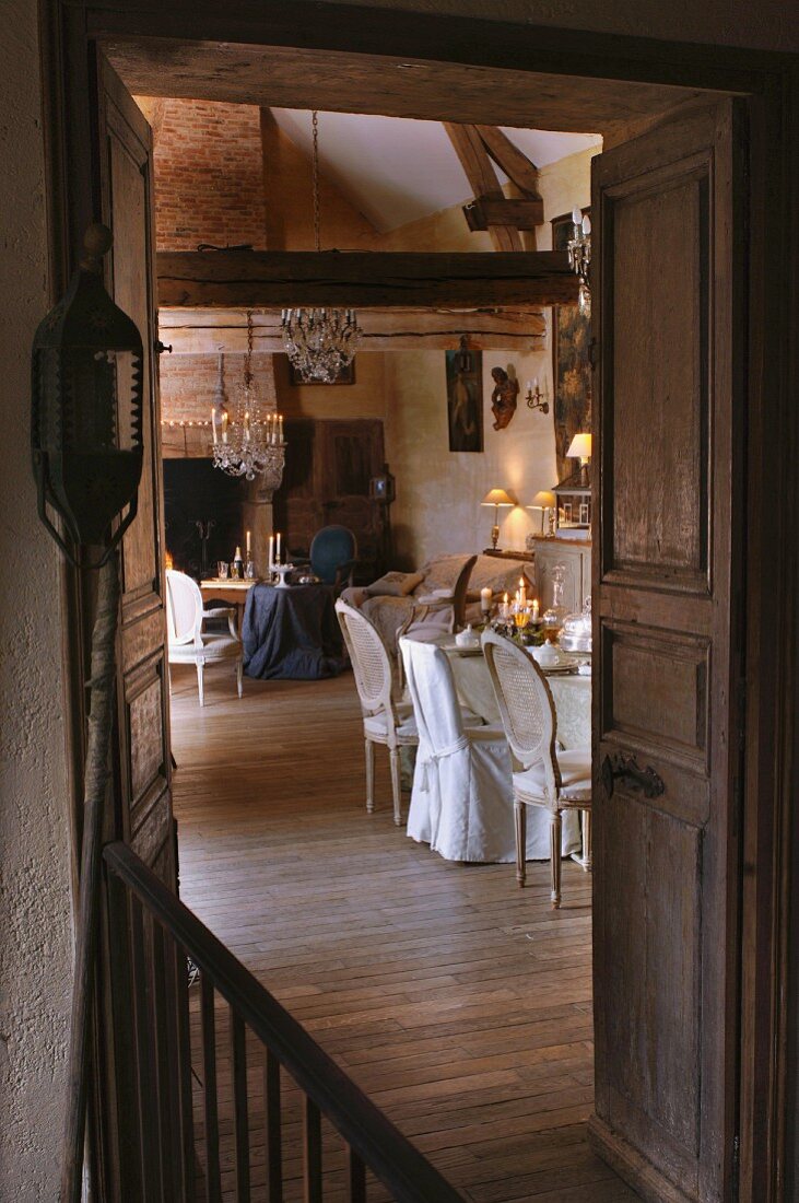 View through open double doors of dining area and seating area in front of fireplace in traditional interior