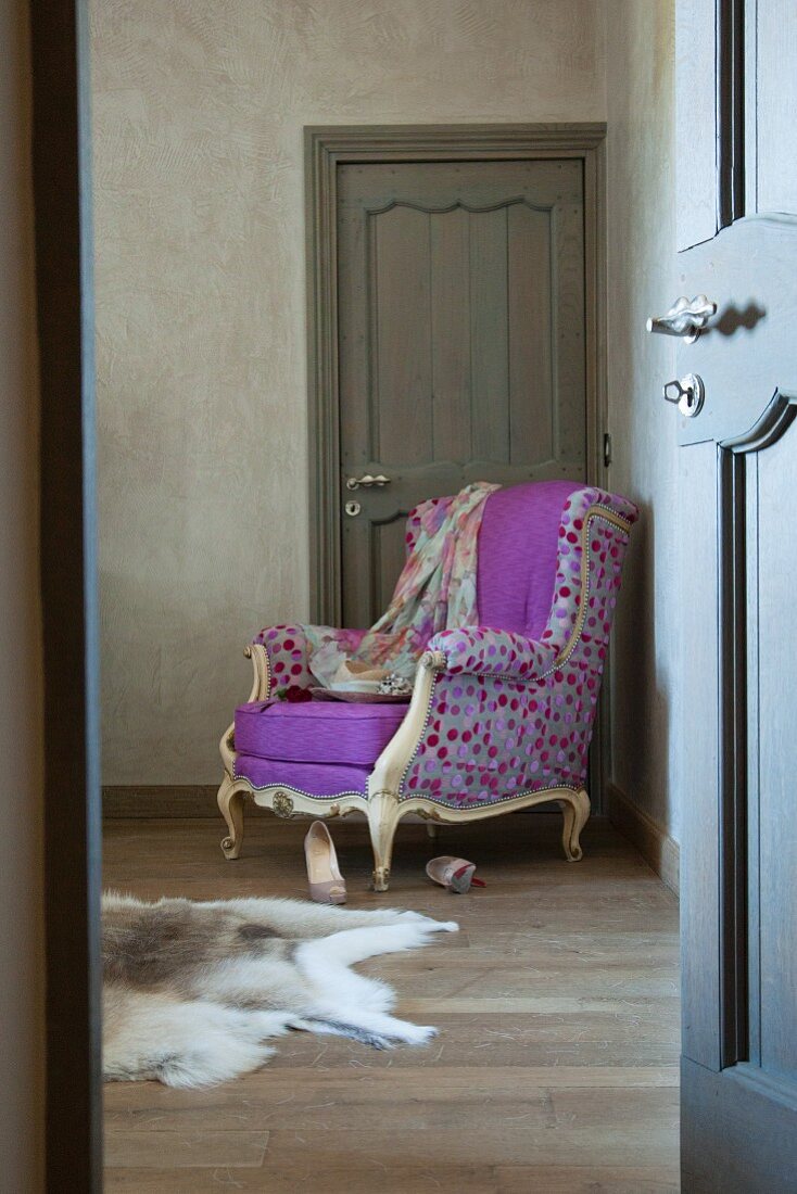 Blick durch offene Tür auf Lesesessel im Rokokostil mit Designer Stoffbezug und farbigem Punktmuster in Zimmertürecke
