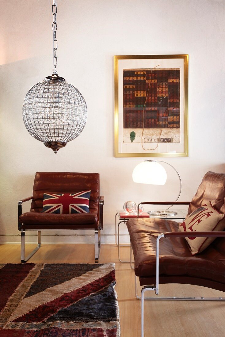 Vintage Ledersessel und Ledercouch, beides mit Edelstahlgestell und Glaskugellampe in einem Wohnzimmer