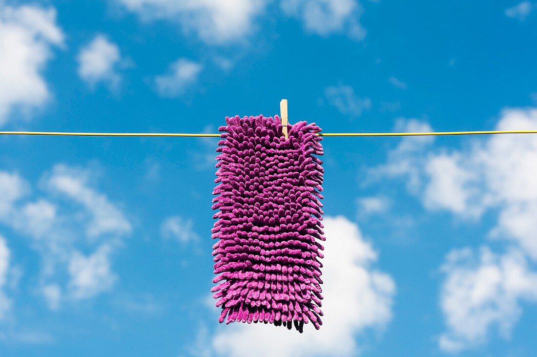 Wischmop hängt auf einer Wäscheleine vor blauem Himmel