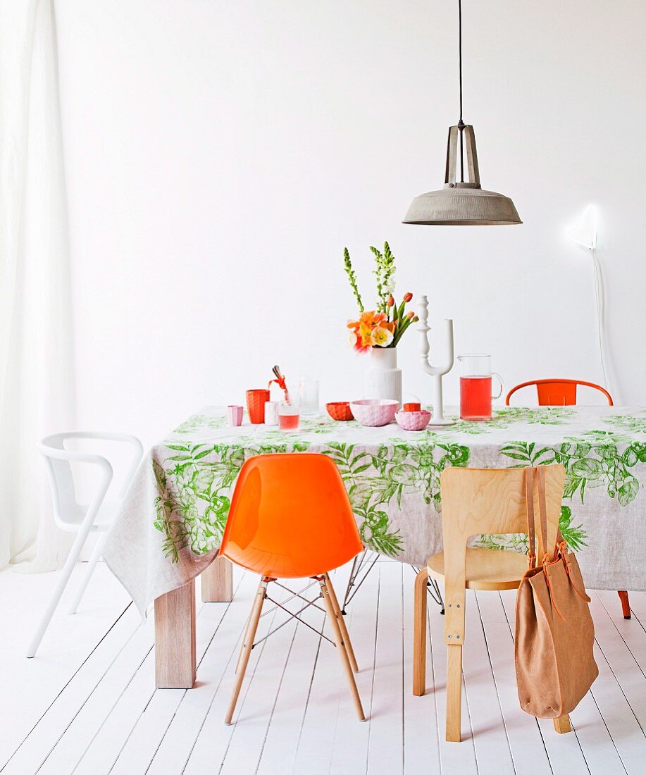 White room with cheerful accents of colour; dining area with various chairs and retro lamp