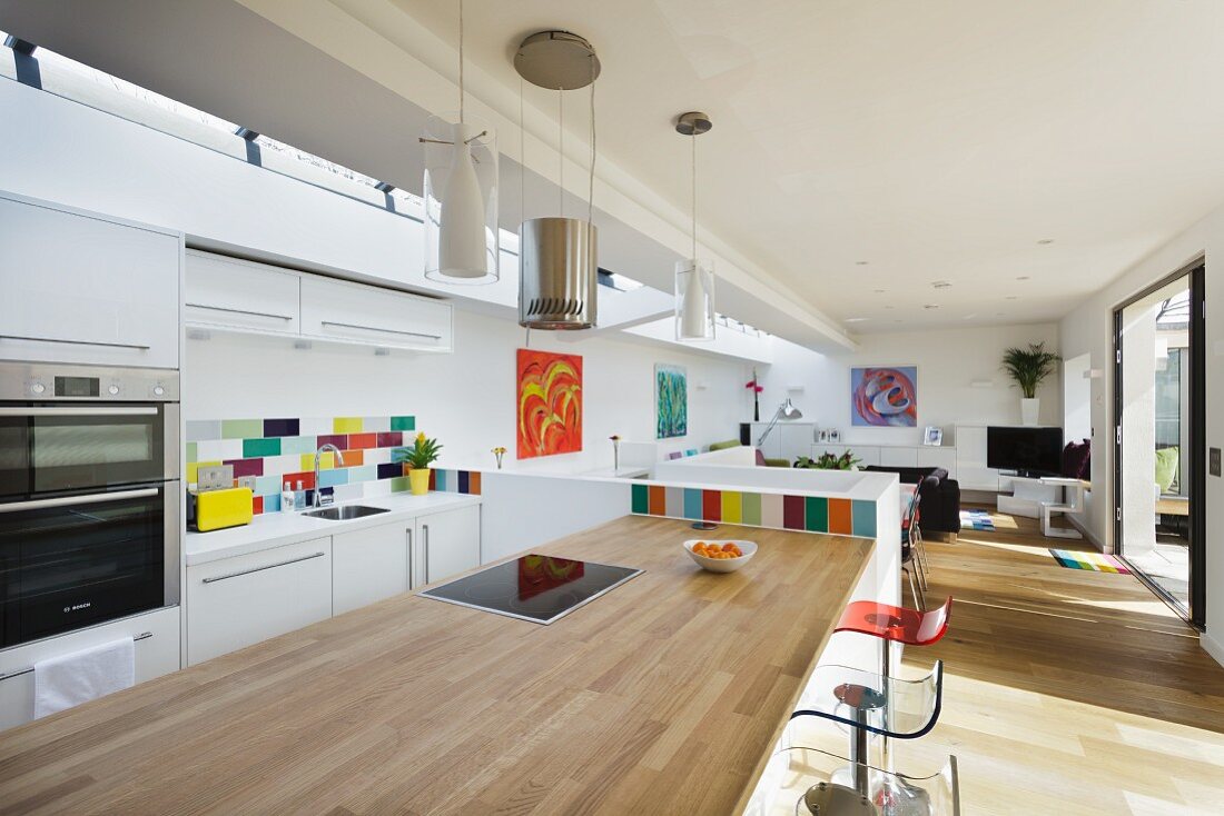 Küchentheke mit hellem Holz als Arbeitsplatte und Barhockern in offenem Wohnraum