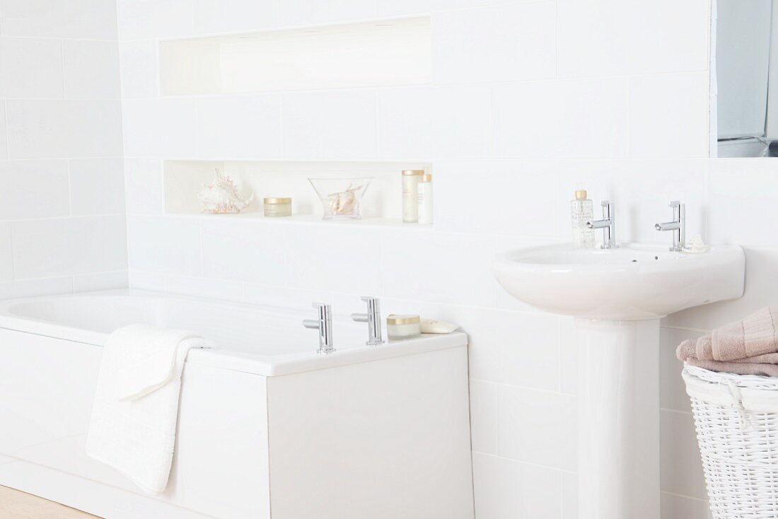 Pedestal washbasin and bathtub in white bathroom