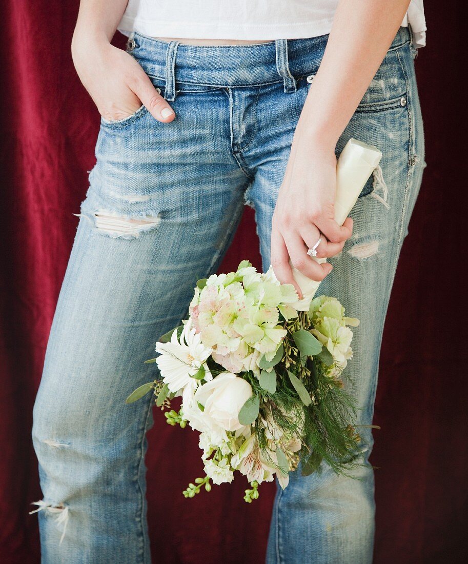 Woman in jeans holding bouquet of flowers