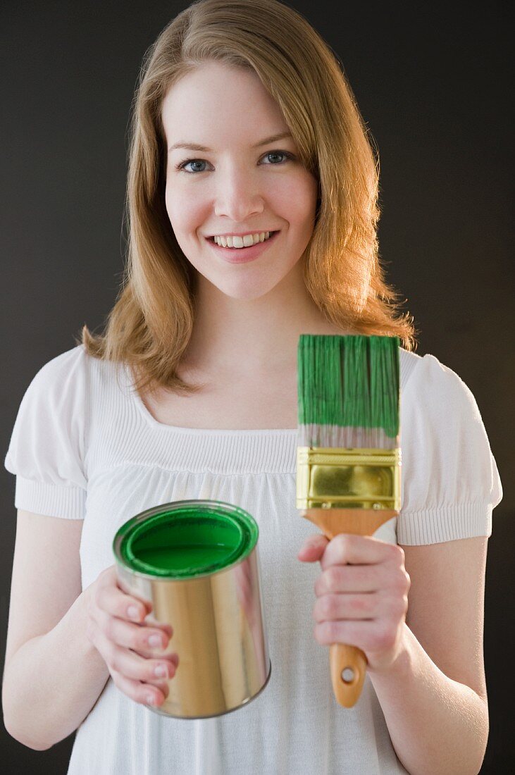 Junge Frau mit grüner Farbe und Pinsel