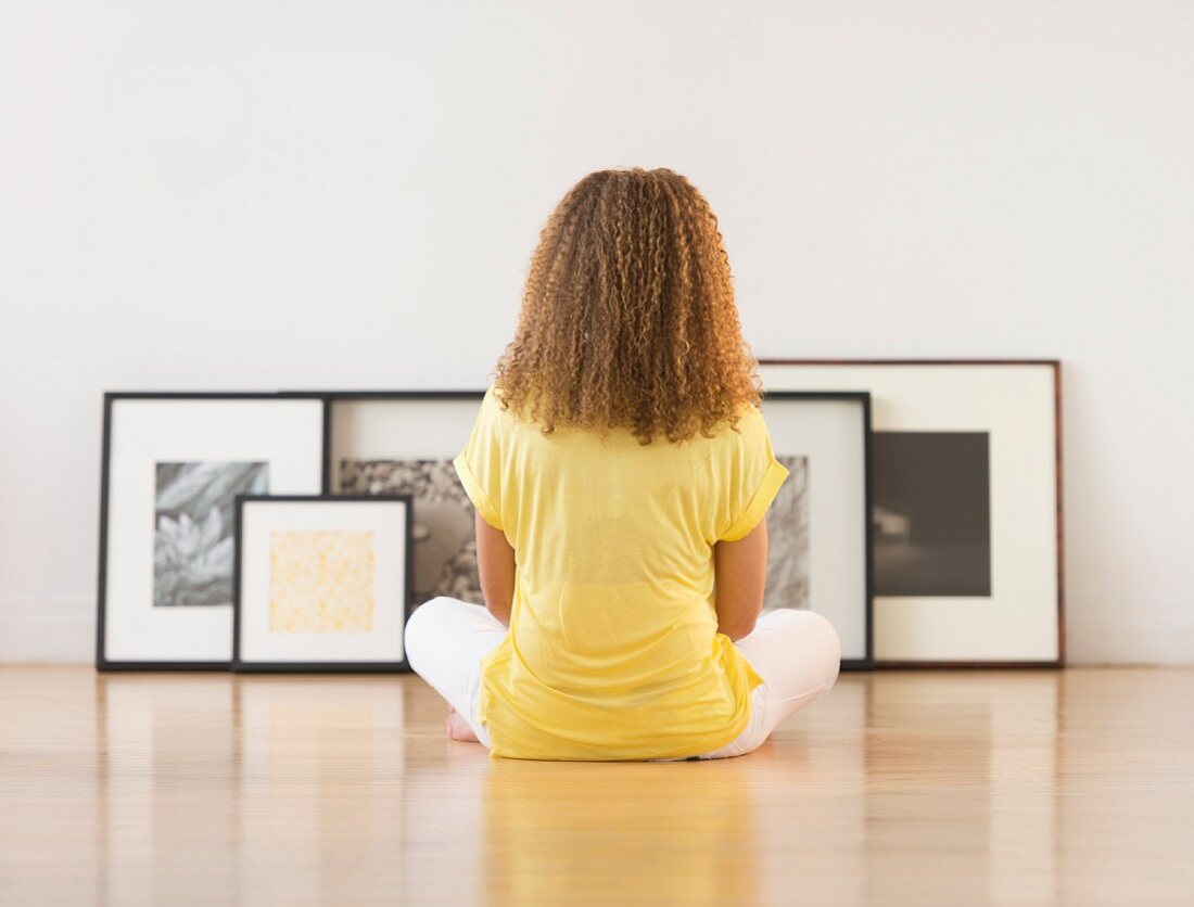 Frau betrachtet Kunstwerke auf dem Boden sitzend