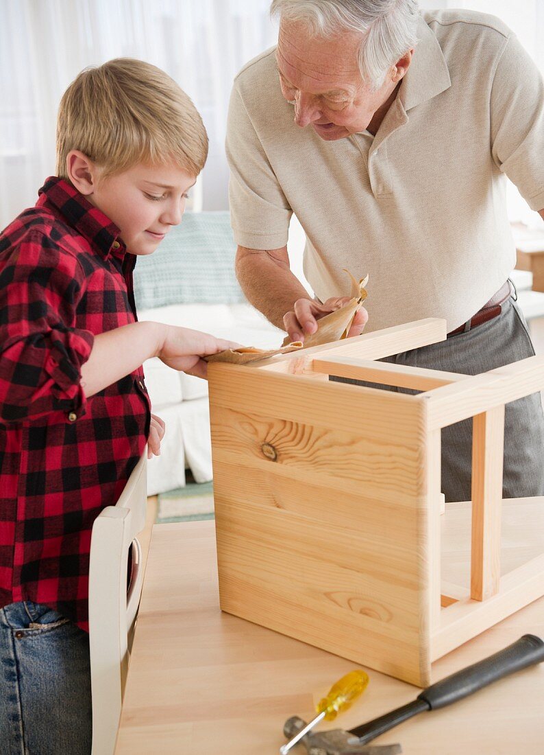 Grandfather and grandson (8-9) improving wooden stool