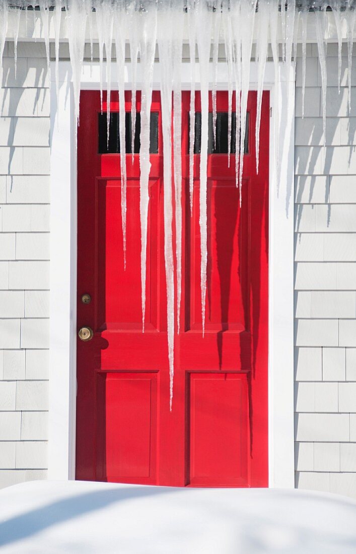 Eiszapfen über einer roten Tür (Maine, USA)
