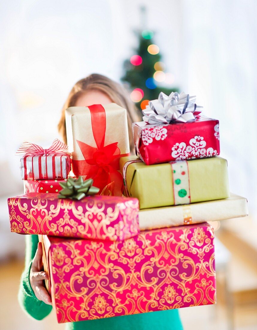 Junge Frau mit Stapel von bunten Weihnachtsgeschenken