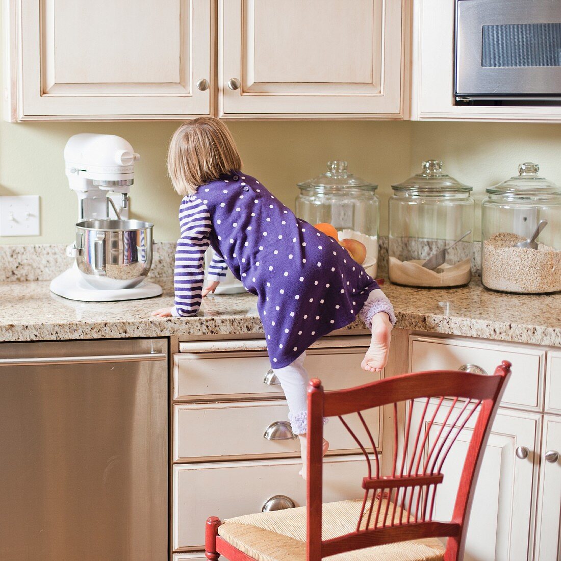 Mädchen klettert auf Schrank in der Küche