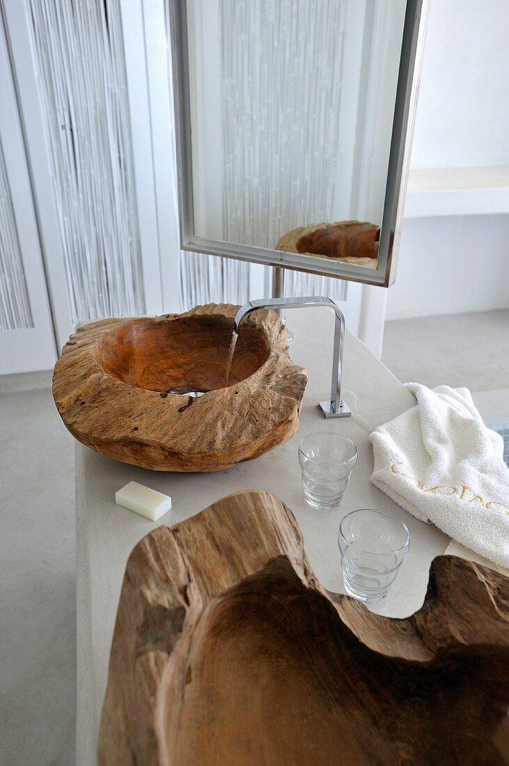 Waschtisch mit Schüssel aus teilweise naturbelassenem, massivem Holz vor Standspiegel