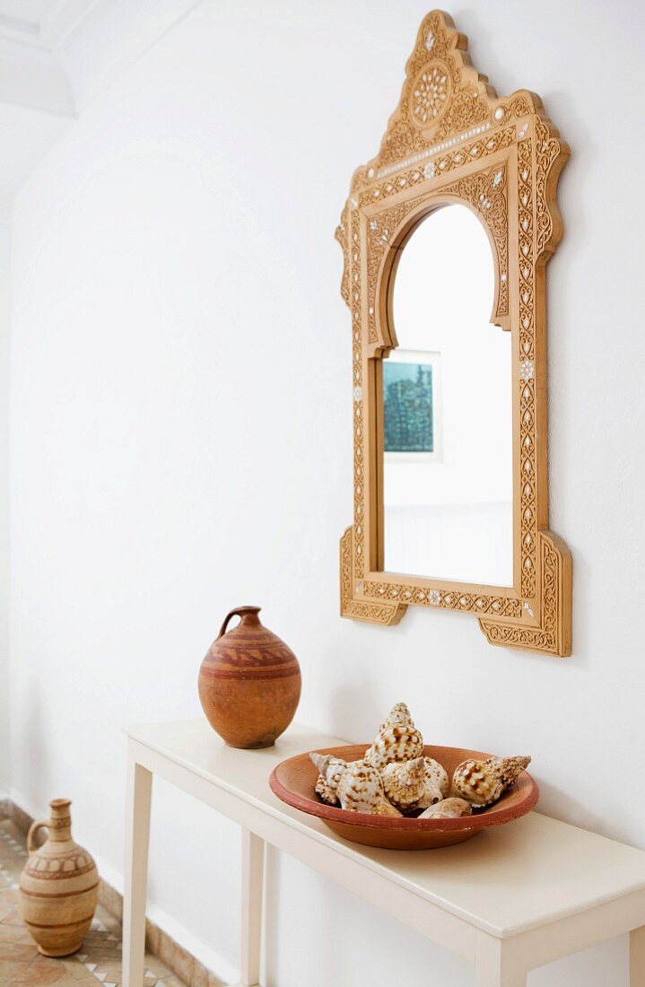 Marokkanischer Spiegel über Konsolentisch mit Tongefäss und Muschelsammlung